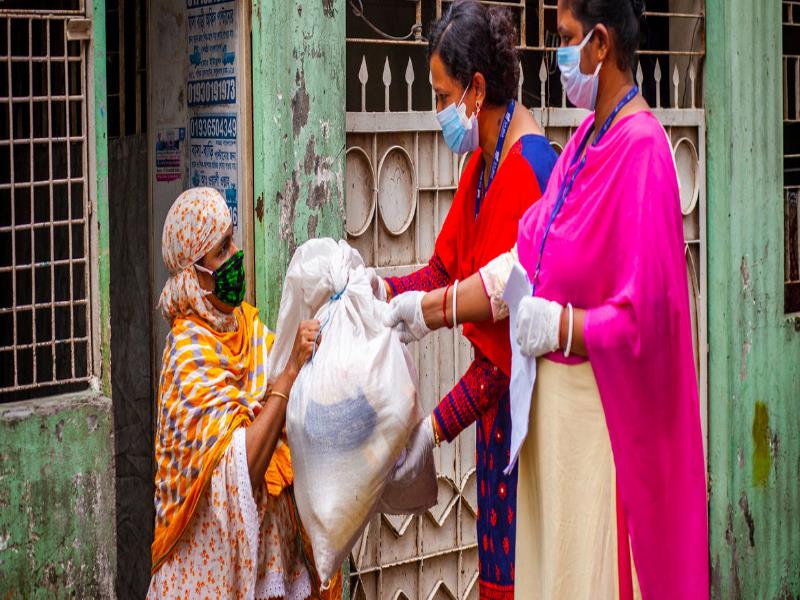 ONU Mujeres/Fahad Kaizer Trabajadoras de programas de desarrollo en Dhaka, Bangladesh, entregan asistencia a una mujer durante la pandemia de COVID-19