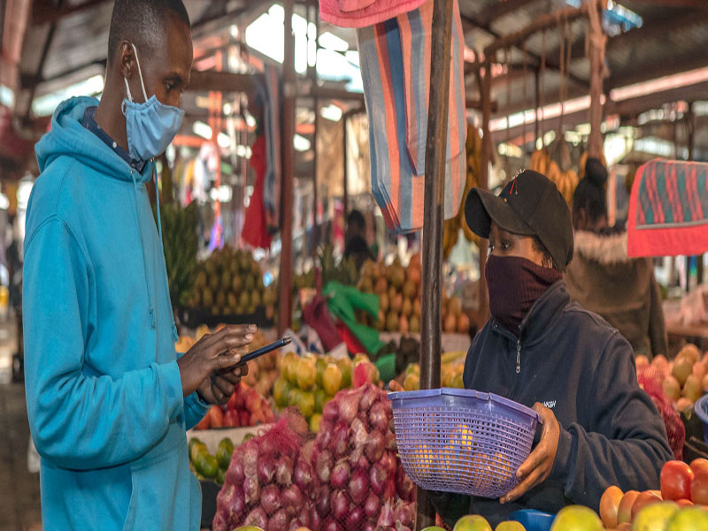 Banco Mundial / Sambrian Mbaabu Un joven compra fruta en un mercado de Kenya