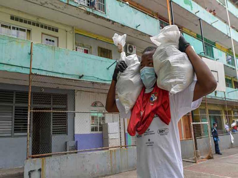 Un voluntario entrega alimentos a familias de bajos ingresos en la ciudad de Panamá durante la pandemia del coronavirus. © Luis ACOSTA / AFP