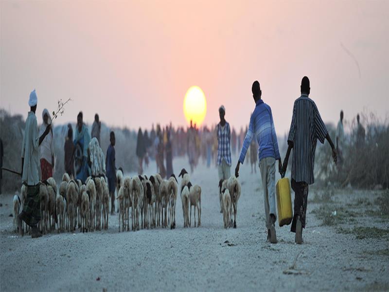 Escena cotidiana en la que se aprecia en el horizonte a un niño cargando garrafas de agua en Jowhar, Somalia (2013). ONU/Tobin Jones