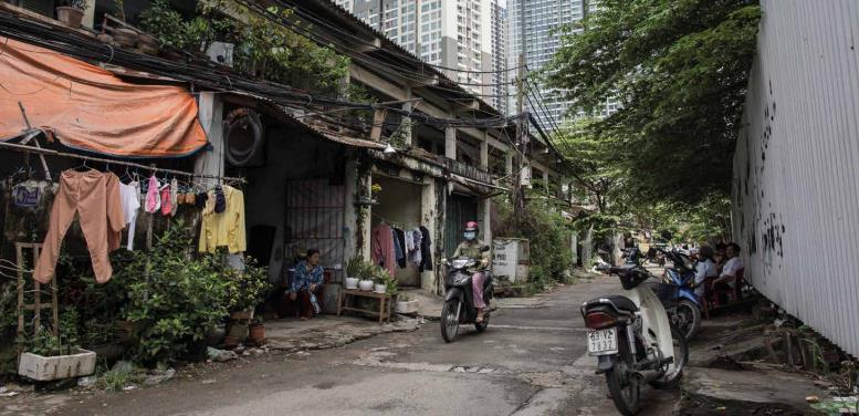 Una mujer se desplaza en moto por un barrio empobrecido rodeado de lujosas urbanizaciones en las afueras de la ciudad de Ho Chi Minh (Vietnam). Foto: Sam Tarling/Oxfam (2017)